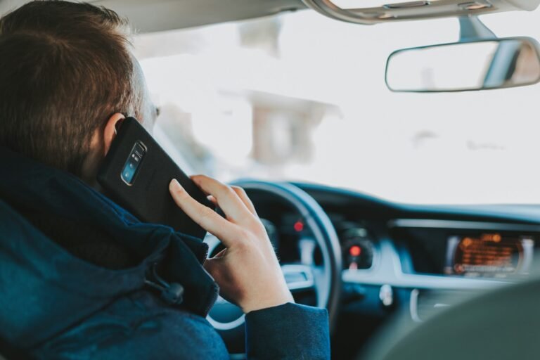 Man in car holding phone with car app