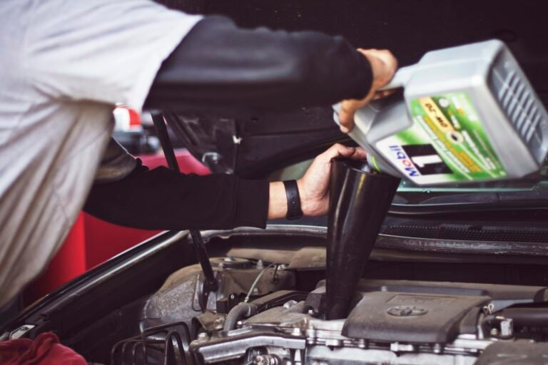 Man doing his own car repair, refilling motor oil